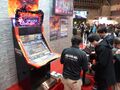 A photo from during JAEPO 2015 shows the game cabinet and tablet terminal.